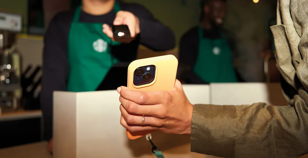 Starbucks Barista scanning the Rewards App from a Customer Phone at the Till